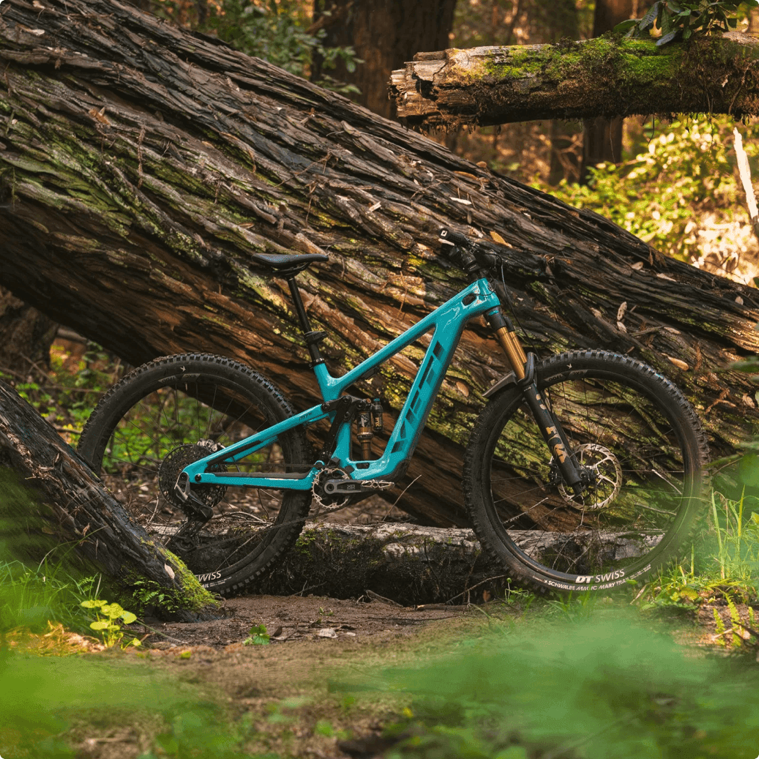 Yeti Cycles turquoise full-suspension mountain bike with DT Swiss wheels on a dirt forest trail