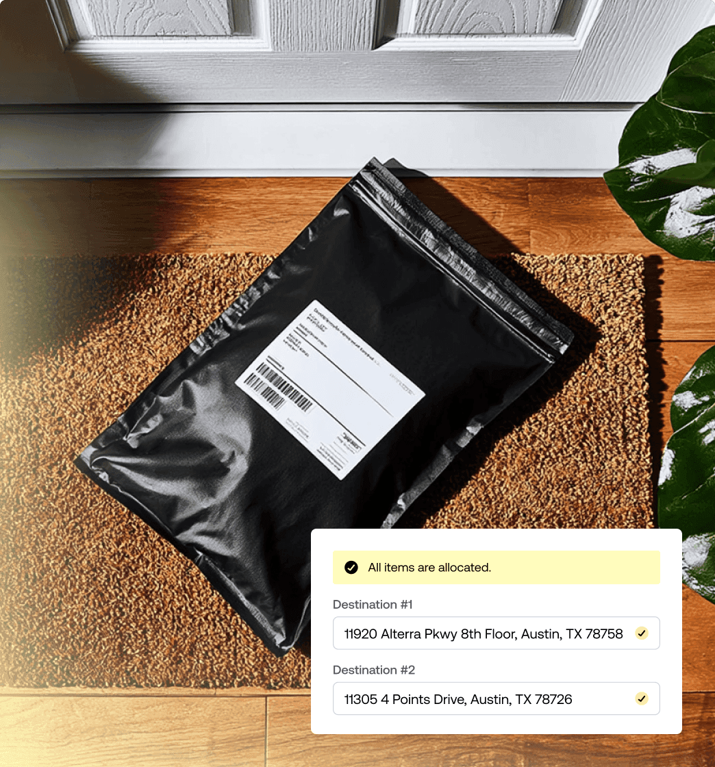 Black mailer package sitting on a welcome mat outside a front door next to house plants.