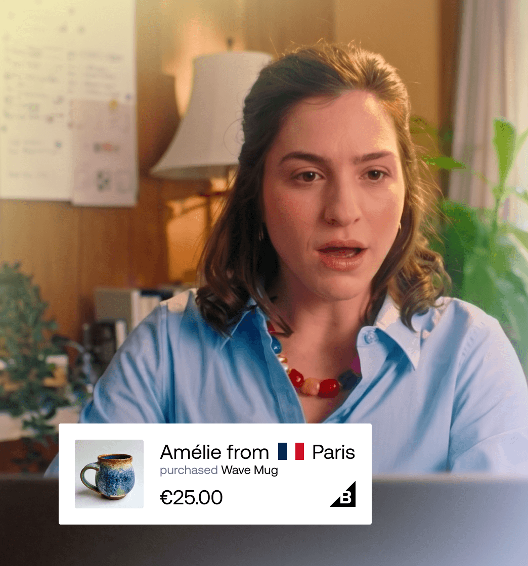 Woman looking at screen with live social proof badge showing Amélie from Paris bought a Wave Mug for €25